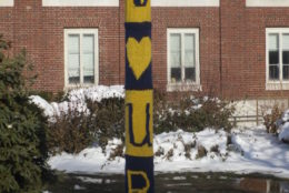 I heart UR wrapper on pole in a snowy day with brick building behind it