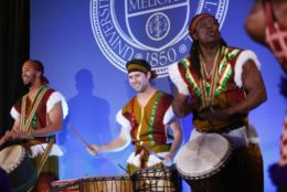 three men on stage with drums