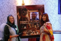 two women posing for photo in front of an art display