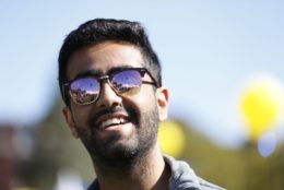 man wearing sunglasses smiling with a blurry background