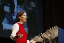 a woman at podium speaking wearing red