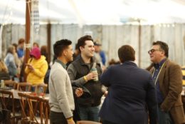 group of four men in a circle talking in meliora village tent