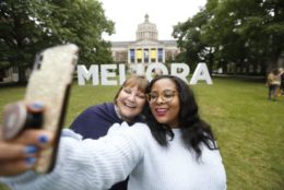 two women taking selfie in front of large meliora letters in quad