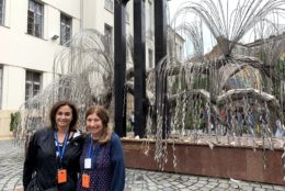 two women posing in front of a sculpture