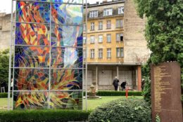 glass sculpture in front of yellow building with a lot of windows