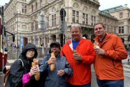 two women and two men with food in hand posing for photo in front of a large building