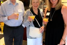 two women and one man posing for photo all with drinks in hand
