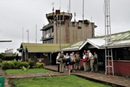 a building in tanzania with tower in background and group of tourists in foreground