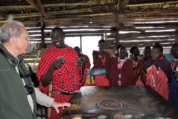 Tanzanians in a building talking to a man with glasses and camera