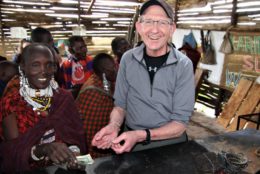 man with cap and glasses smiling and posing with Tanzanians