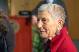 older woman with short hair and red jacket looking into the distance