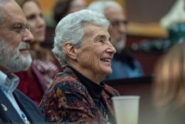 older woman smiling watching a talk