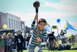 younger kid with a giant hammer at carnival game