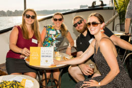 three women and one man wearing sunglasses posing for photo seated on a boat