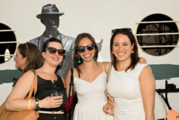 three women, two wearing sunglasses posting with george eastman cutout