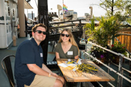 man and woman wearing sunglasses posing for photo seated at outdoor table