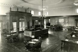 1926 black/white photo of empty lobby with front desk and tables and chairs