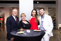 two men and two women smiling and posing for photo in front of a table