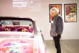 person smiling and looking down at a colorful classic car