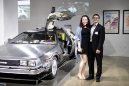 man and woman posing for photo next to deloreon from back to the future