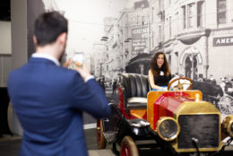 man taking photo of woman sitting in antique car