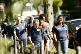 group walking down sidewalk wearing matching blue alumni t-shirts