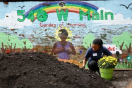 woman with pot of yellow flowers next to mound of dirt