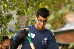 man in glasses wearing blue UR shirt smiling holding a shovel