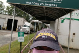 woman in cap and pink mask taking selfie in front of regional food bank entrance