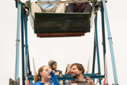 man with arms up on a ferris wheel