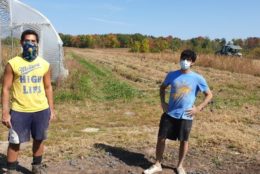 two men posing for photo in a large farm field