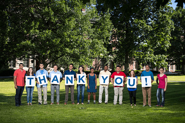 group of people holding "Thank You!" sign and smiling for camera