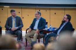 three men seated in suits giving talk