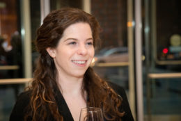 woman smiling with long brown hair looking out in distance