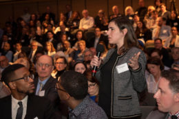 woman with mic standing in audience asking a question