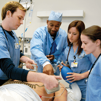 a nurse instructor is teaching three nurses with hands on training on a patient.