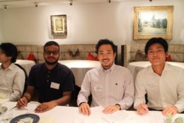 four men at a dinner table posing for photo