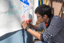 male student writing a note on a white board
