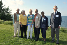 three women and three men posing outdoors for a photo in front of the lake