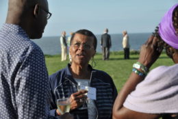 two women and a man outdoors having a drink and conversation