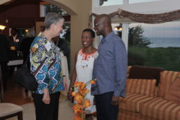 two women and a man standing in front of couch talking