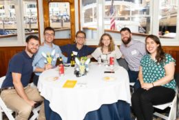 four men two women posing for photo at a table