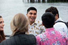 man with a smile in a circle of friends with water front in background