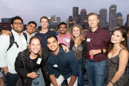 group of young alumni posing for photo with city in background
