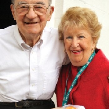 an elderly couple smile together as they pose for a picture together.