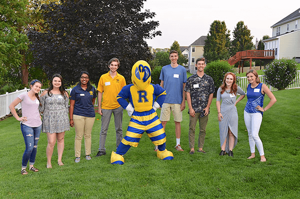 Volunteers standing with Rocky mascot on a lawn