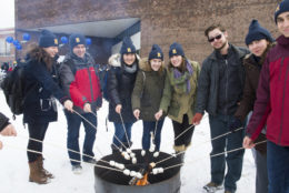 group of people roasting marsh mellows on a cold, snowy day