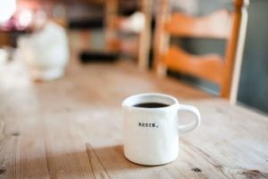 a full coffee mug with the word begin sits on a table