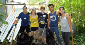 five volunteers smiling for photo while doing yard work