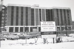 new strong memorial hospital sign in front of building with black/white photo